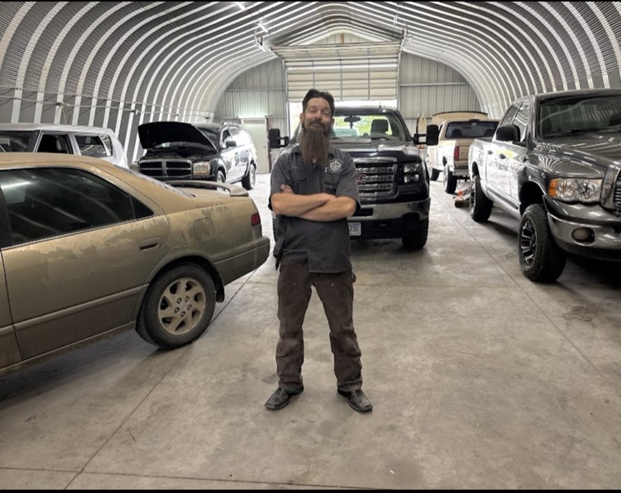 Trevor, owner of TDC Automotive & Light Duty Diesel, standing in his Cheyenne, Wyoming shop surrounded by customer trucks